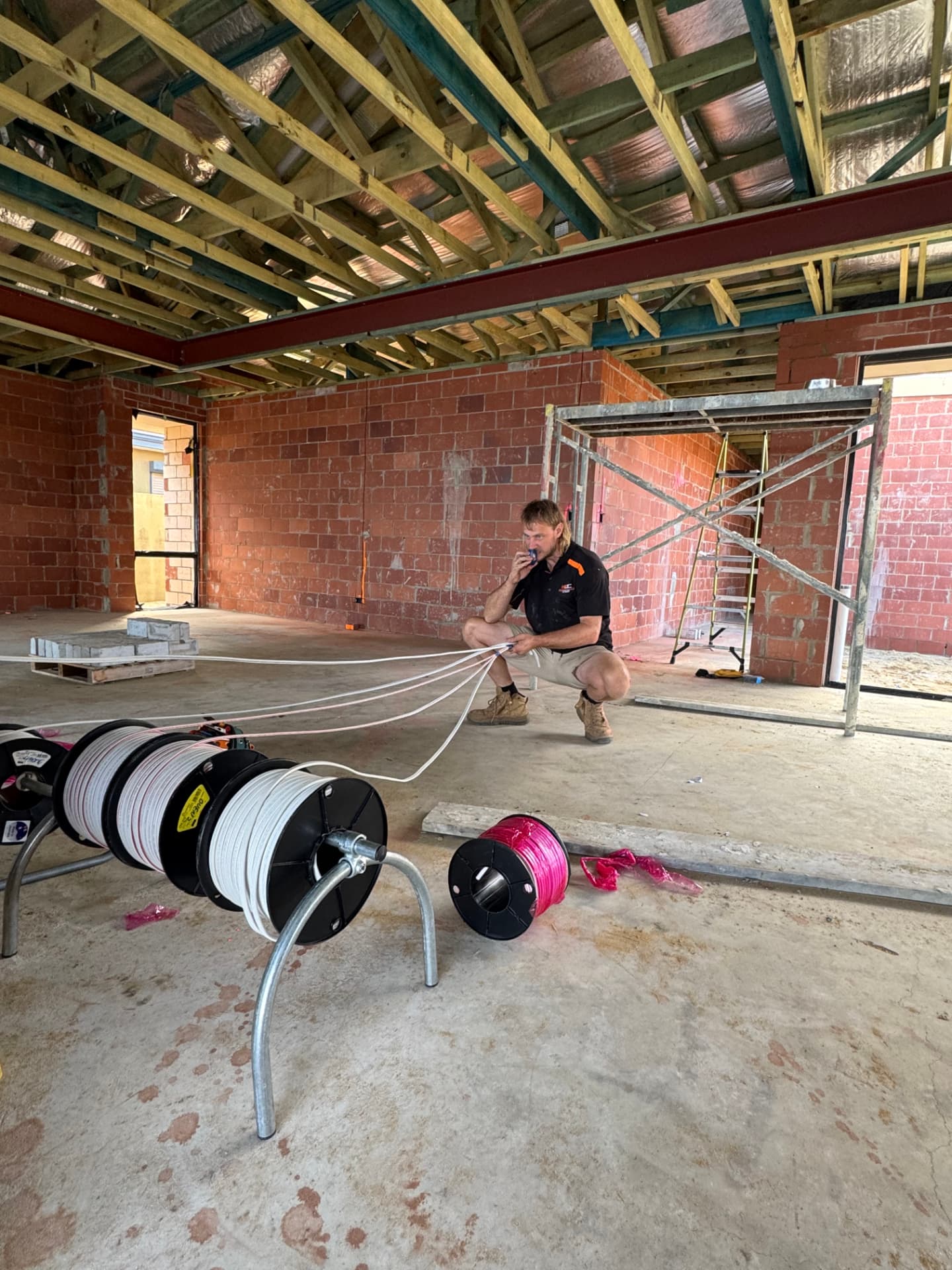 McGuires Electrical electrician pulling multiple electrical circuits through framed timber trusses during a home build