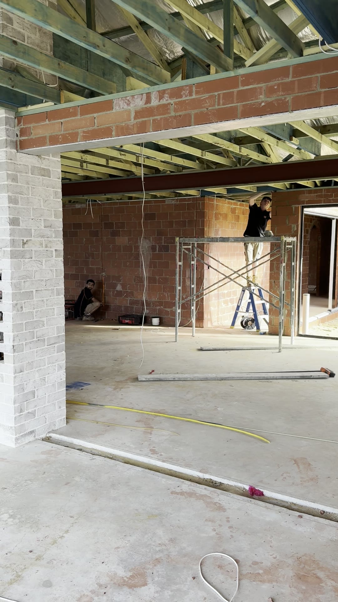 Two electricians working on scaffolding during the electrical rough-in of a new Mandurah canals home
