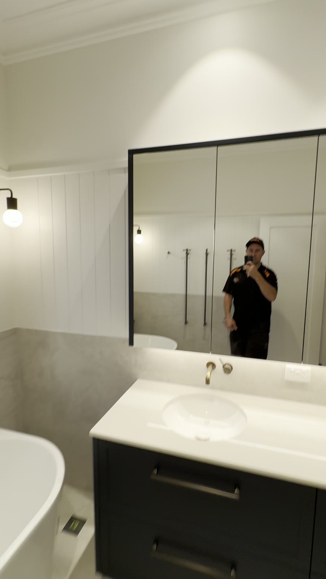Renovated Nedlands bathroom with freestanding bath, black-framed mirror cabinet and wall sconce lighting