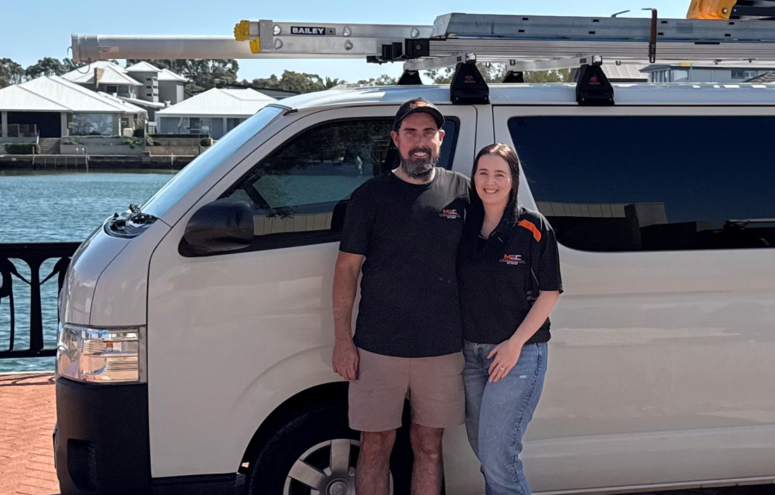 Husband and wife team Matthew and Emily McGuire in McGuires Electrical Contractors branded shirts in front of their work van in Perth