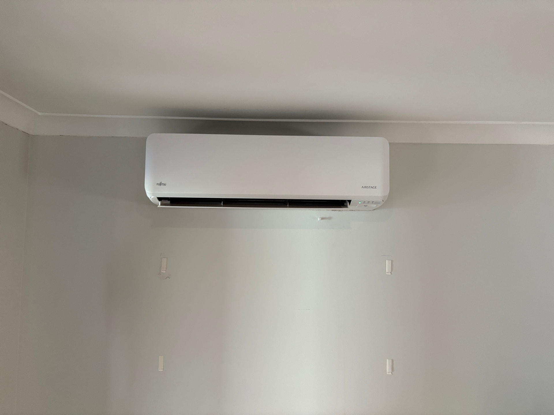Fujitsu Airstage split system installed high on a wall in a Perth home by McGuires Electrical